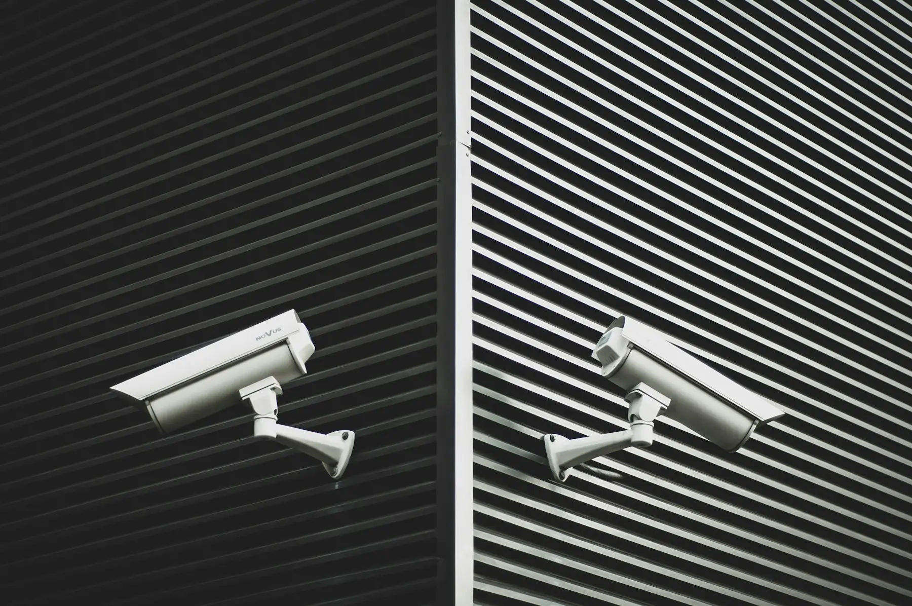 Two mounted CCTV cameras on a corrugated industrial facade